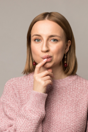Young woman with her finger near pursed lips, portraying uncertainty about composite fillings cost