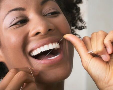 Closeup of a woman smiling while flossing her teeth